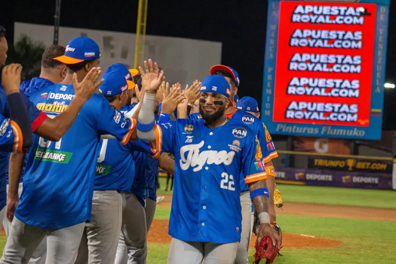 Peloteros de Tigres de Aragua, con uniformes azules, chocan las manos sobre el terreno del José Bernardo Pérez.