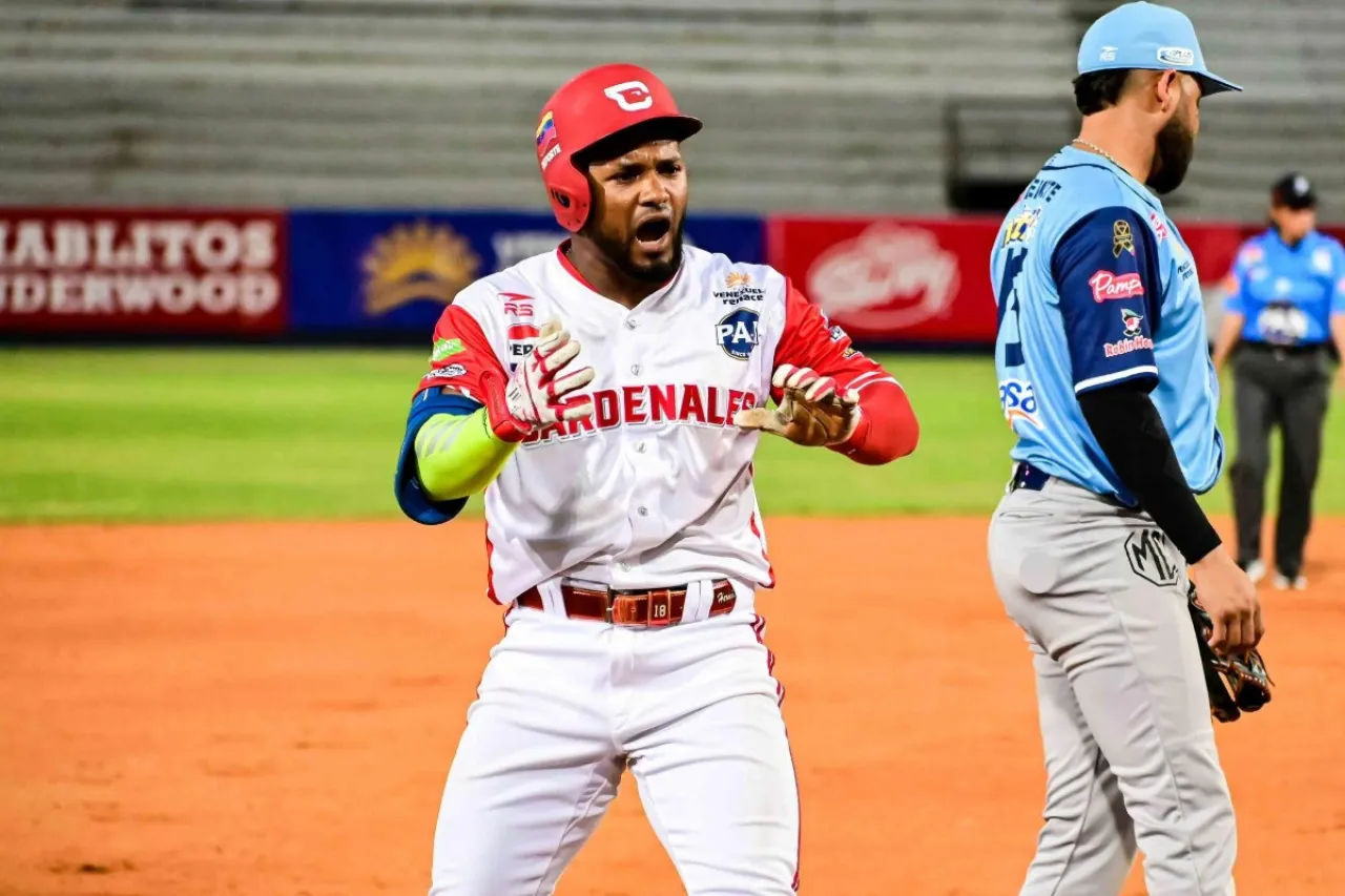 Yonny Hernández, con casco rojo y uniforme de Cardenales, celebra junto a un defensor de Magallanes.