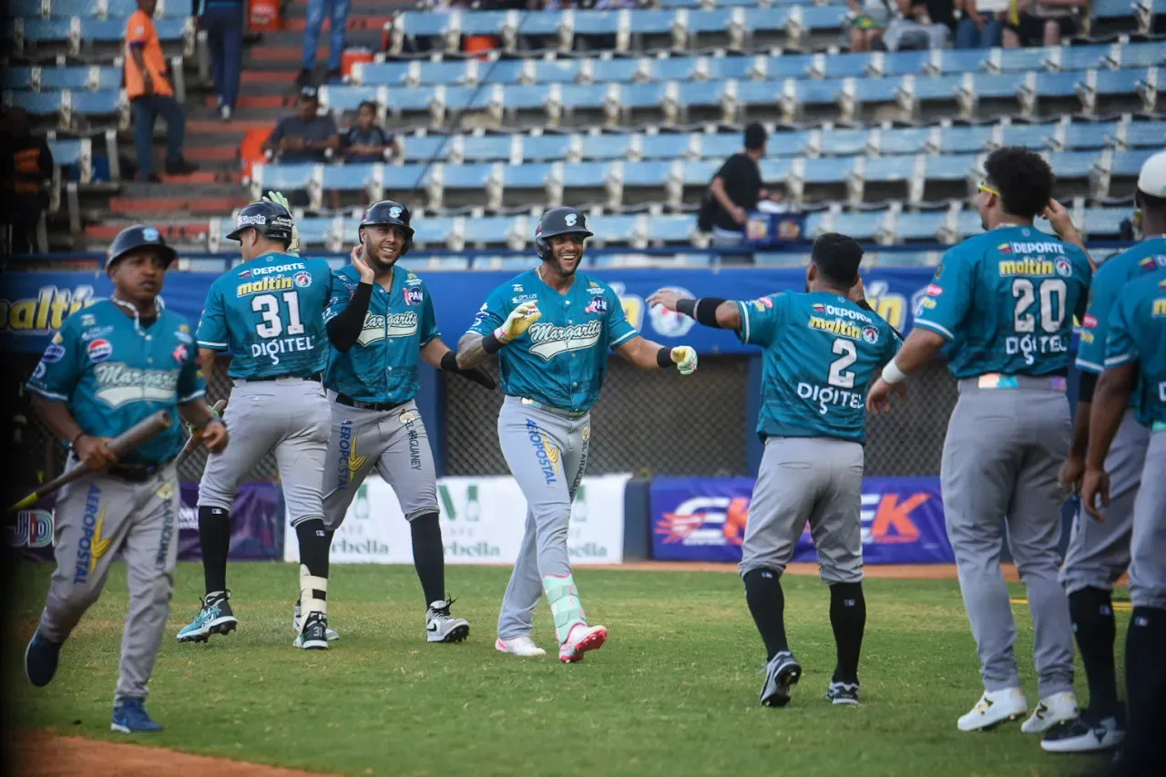 Peloteros de Bravos de Margarita, con uniformes turquesa y pantalones grises, celebran sobre el terreno en Maracaibo.